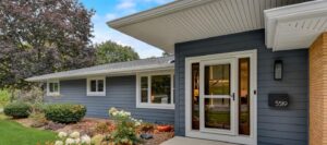 Ranch style home with white trimmed windows and large awning over porch, blue siding
